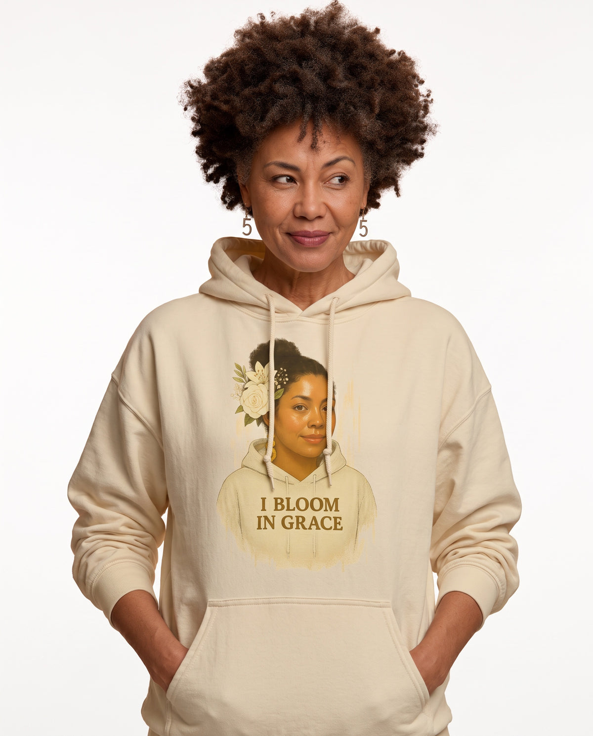 Charmaine, a woman in her 40s with a curly afro and freckles, wearing the I Bloom In Grace Exclusive Hoodie in Gardenia. Hands On 5th St.