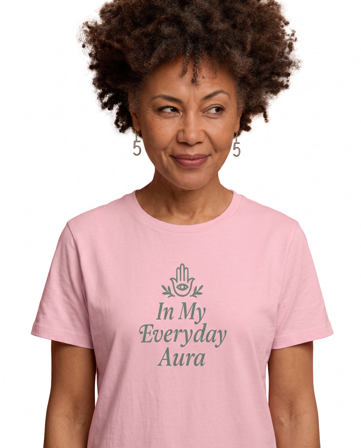 Charmaine, a woman in her 40s with a curly afro and freckles, wearing the In My Everyday Aura Signature Tee in Pink with an embellished Hamsa. Hands On 5th St.