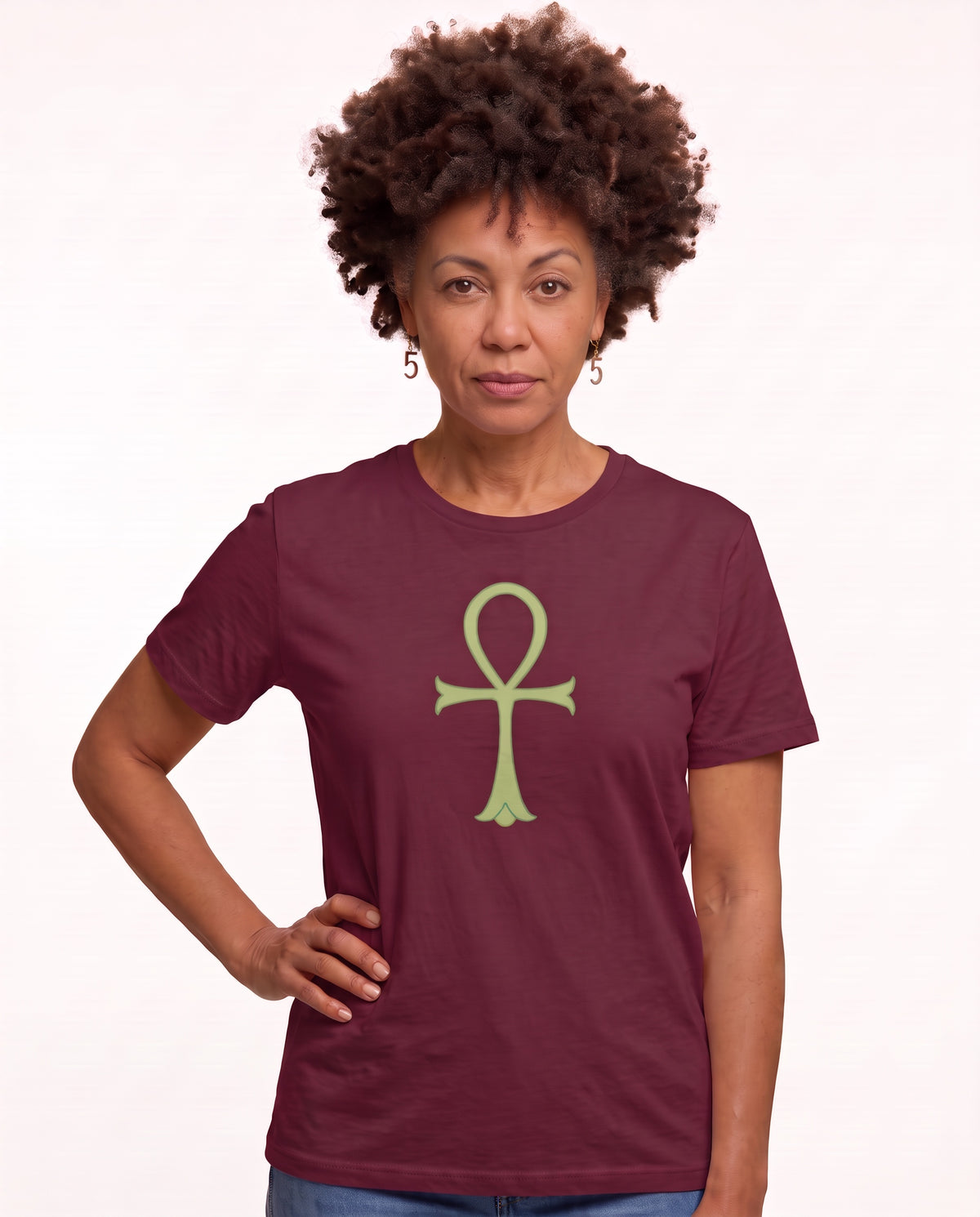 Charmaine, a woman in her 40s with a curly afro and freckles, wearing the Minimalist Ankh Exclusive Tee in Maroon with a sage green Ankh. Hands On 5th St.