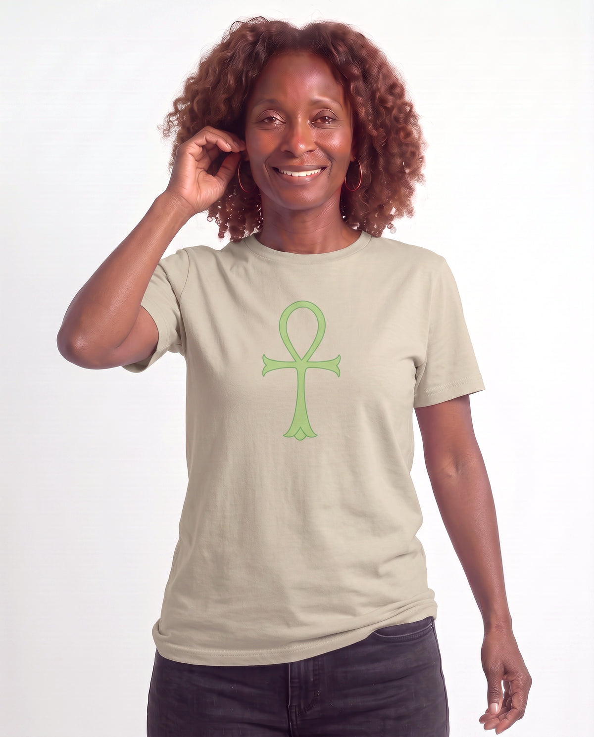Grace, a Black woman in her 50s with shoulder-length auburn curls and gold hoops, wearing the Minimalist Ankh Exclusive Tee in Heather Stone with a sage green Ankh. Hands On 5th St.